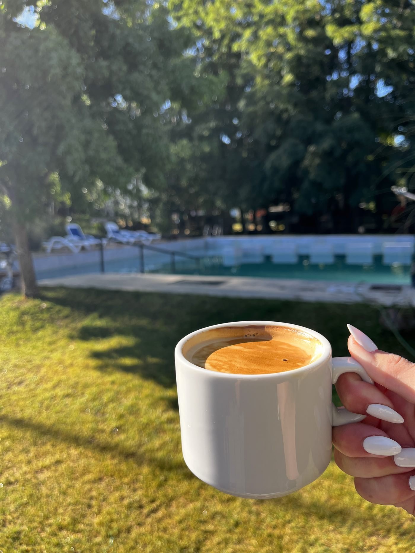 Un café por la mañana sobre el césped, junto a la pileta